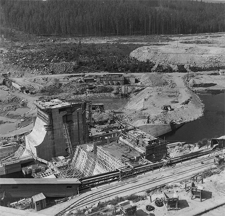 Vodní elektrárna Lipno, hráz Lipno I., 2. stavební jímka - betonáž gravitačních bloků a příprava podloží pro sypání zemní hráze, duben 1956, historické foto