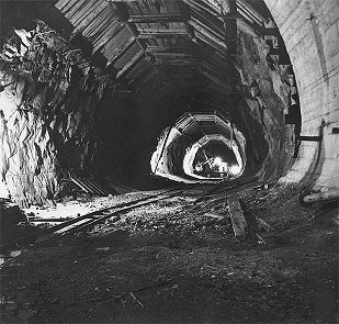 Hydro plant Lipno, waste tunnel, transport of digger D 500 into underground engine room, at ceiling of tunnel hangs timbering, February 1959, historical photo 