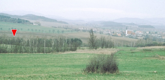 Pohled na Kájov od jihu, červenou šipkou v levé části je vyznačena přibližná poloha pravěkého sídliště., foto: P. Zavřel